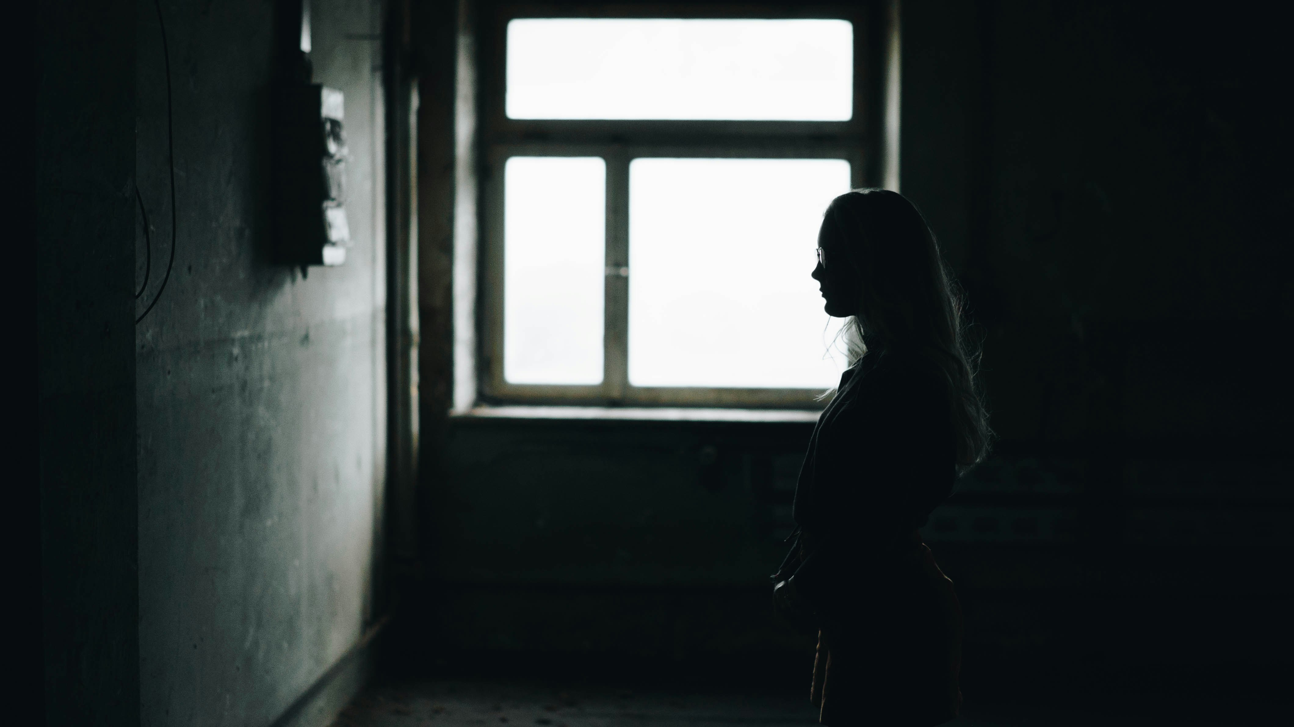 silhouette of woman standing while facing wall inside room